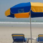 A blue and gold beach umbrella standing over two matching chairs 