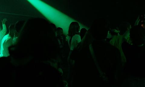 Partygoers dance in an Emo club with lime green lights.