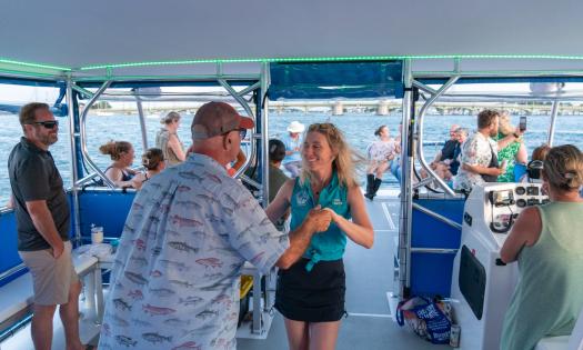 A crew member and a guest dance aboard a Florida Water Tours boat