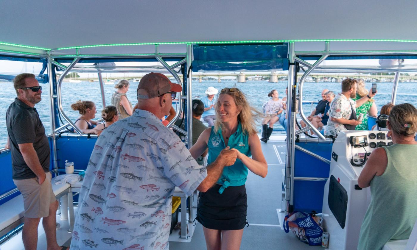 A crew member and a guest dance aboard a Florida Water Tours boat