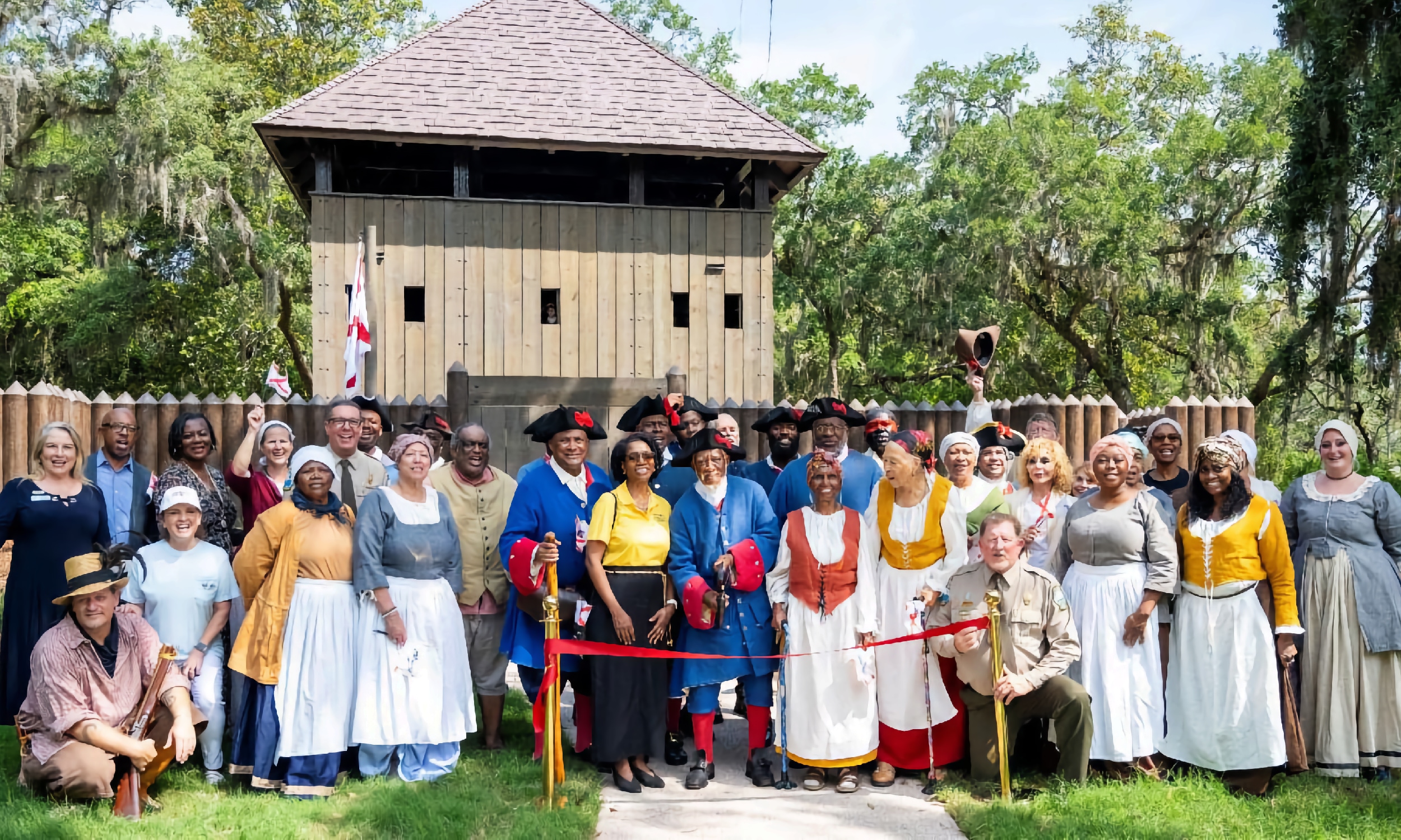People, most in 1700s garb, at a ribbon cutting ceremony for the newly constructed replica of Fort Mose