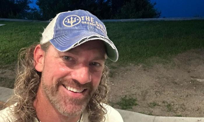 Singer songwriter Joe Downing smiling, at the waterside