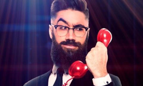 Peter Antoniou holds a phone in his hand and poses in a suit.