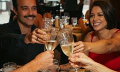 A couple raise their glasses with another couple over dinner