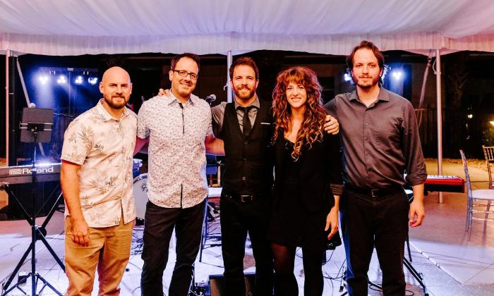Five band members, standing shoulder to shoulder before a reception