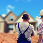 A full color image of two men from behind pointing at a house in the background. One is wearing a hard hat and the other overalls. There is a pile of dirt between them and the house.